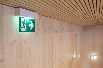 green illuminated emergency lights show way for escape direction in a modern wooden building