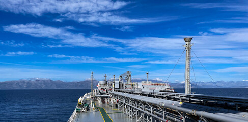 View from the deck of a gas tanker to the seashore, mountains can be seen in the distance. Calm...