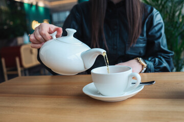 A girl in a cafe pours tea into cups. Beautiful cozy photo.
