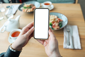 Hands with an isolated phone screen on the background of food in a cafe. Place for your review or...