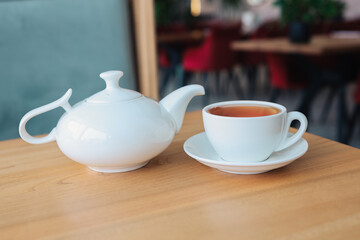 Tea in a cup with a teapot on a table in a restaurant