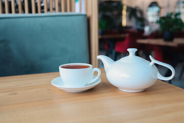 Tea in a cup with a teapot on a table in a restaurant