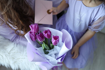 Happy mother's day! Child daughter congratulates mom and gives her flowers tulips.