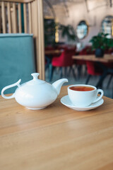 Tea in a cup with a teapot on a table in a restaurant