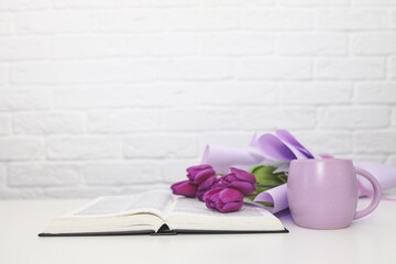 Bible with coffee cup and flowers on white table, christian background with copy space