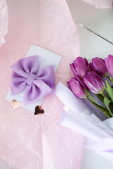 Beautiful purple hair bow in a gift box and a bouquet of flowers on the table