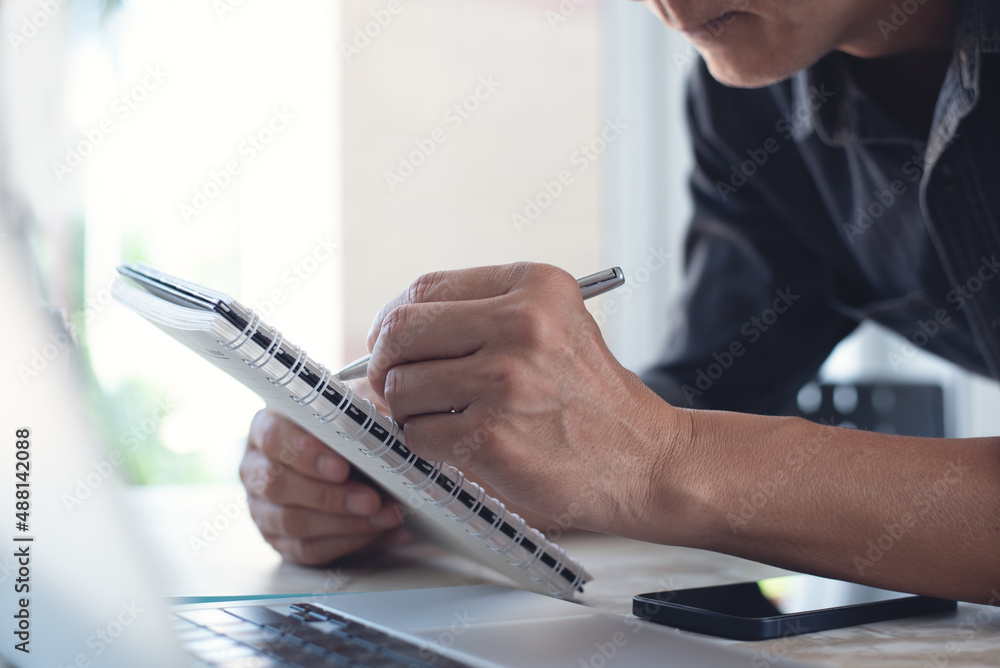 Poster asian business man hand with a pen writing on notebook, internet networking and working on laptop co