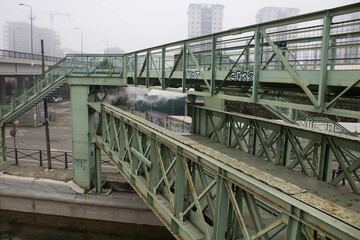 Fototapeta premium Milan, Don Lorenzo Milani overpass, evocative image of the iron bridge along the Naviglio used to connect a ceramic factory with the railway under a gray sky