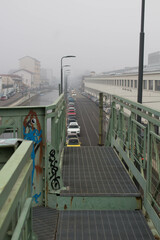 Naklejka premium Milan, Don Lorenzo Milani overpass, evocative image of the iron bridge along the Naviglio used to connect a ceramic factory with the railway under a gray sky