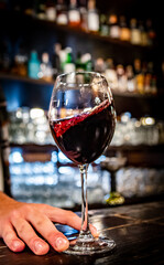 bartender hold red wine into a glass in cafe or bar