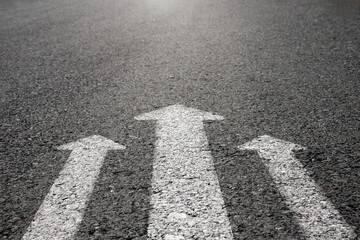 Arrow symbols darting forward on paved road.