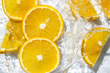 Orange slices in water on a white background. Orange slices fall into the water. Refreshing citrus fruit