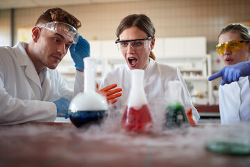 Young chemistry students are astounded by chemical reaction of an experiment in a university...