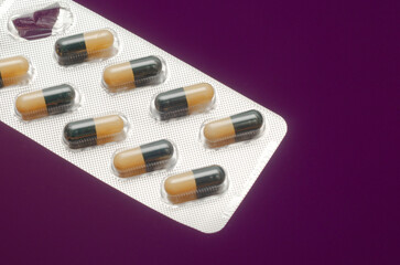 pills in oval capsules in a blister pack on a purple background