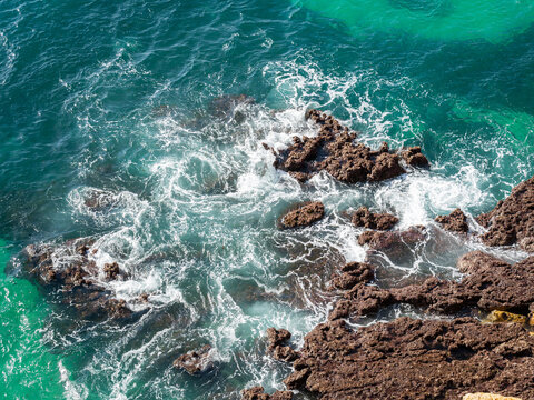 Turquoise seawater breaking against rocks 1