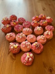 A close up view of freshly baked pink valentines day cup cakes, with pink icing and sprinkles