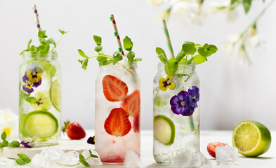Cold Infused detox water with edible flowers, strawberry and mint leaves. Refreshing summer drink.