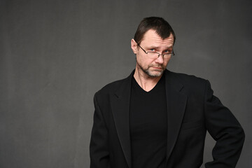 Fototapeta premium Portrait of an adult man in glasses with disbelief on a gray background