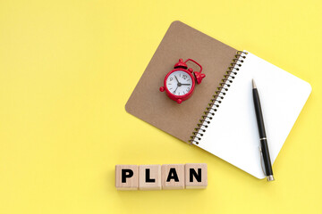 Notepad and pen on the background. Wooden cubes with word plan.