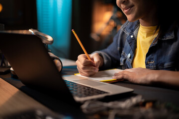 Girl's hands taking notes with pencil in notebook, laptop, headphones, teenage girl has remote lessons, distance learning, online school