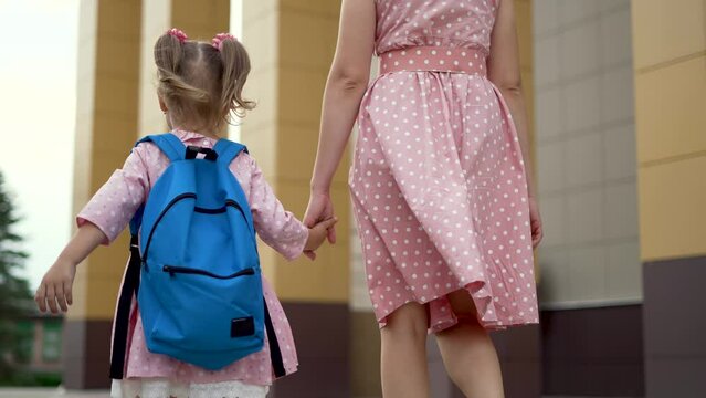 Happy family back to school. Mom and daughter go to school by hand. Girl with backpack holds her mother by hand. Happy family concept. Back to school. Mom and daughter go to school with a backpack
