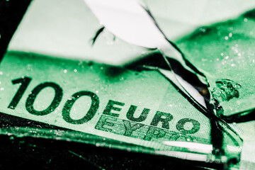 one hundred euro banknotes with green broken glass. financial crisis concept