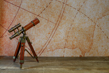 Vintage telescope on retro map background on wooden floor