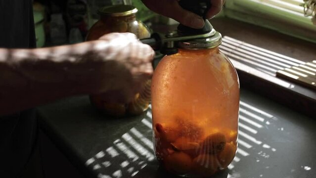 A man rolls up a jar of fruit preserves.