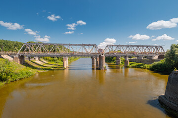 Railroad bridge over muddy river at city suburbs