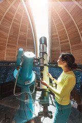 Happy woman in a space observatory looks at a meteorite or the sun through a professional optical telescope. Astronomy occupation and study concept - obrazy, fototapety, plakaty