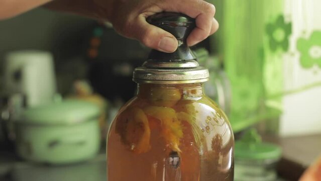 A man rolls up a jar of fruit preserves.