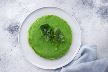 Green thin pancakes with spinach on gray background. Vegan food concept. top view