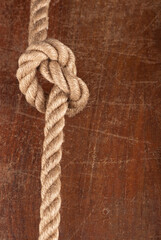 Fototapeta na wymiar Knot on Wood. Rope with Reef Knot on Wood Texture Background
