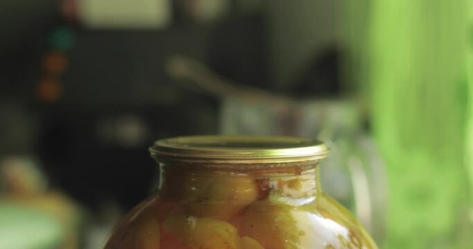 A man rolls up a jar of fruit preserves.