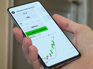 Stock exchange market chart, etf data electric automobile on smartphone. Business analysis of a trend. Invest in electric car fund. Buying strategic electric-vehicle ETF blue chips.