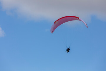 Paragliders in bright blue sky, tandem of instructor and beginner