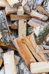 Chopped birch firewood lies in a heap on the snow in winter - 488168012