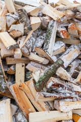 Chopped birch firewood lies in a heap on the snow in winter - 488168017