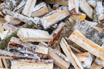Chopped birch firewood lies in a heap on the snow in winter - 488168037