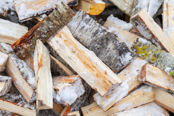 Chopped birch firewood lies in a heap on the snow in winter - 488168062