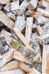 Chopped birch firewood lies in a heap on the snow in winter - 488168070
