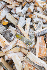 Chopped birch firewood lies in a heap on the snow in winter - 488168081