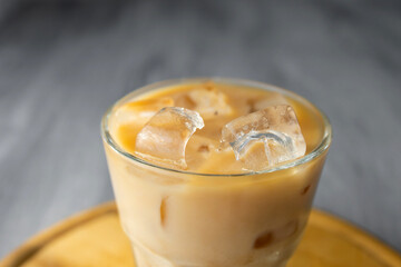 Close up of glass of a iced coffee with cream milk on a wood desk. Cold brew coffee drink with ice....