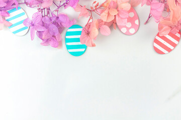 Colorful easter eggs and flowers. Border design with pink spring flowers. Happy easter greetings concept, holiday decoration background with copy space, flat lay, top view photo