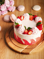 Delicious strawberry gradient colored spicy cake with strawberries. Strawberry cake on the table on March 8, Mother's Day, Valentine's Day or birthday. Wooden background and pink rose, flowers. Text.