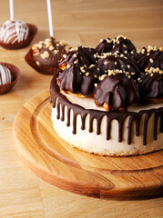 Birthday souffle cake with chocolate decor and sprinkled with nuts on a wooden background. Bird's milk. Space for copying. The concept of celebration. March 8, Mother's Day, birthday. Space for text.