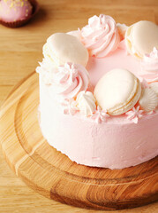Cake for a girl. Delicate strawberry pink cake decorated with white macaroons on a wooden background. Strawberry cake on the table on March 8, Mother's Day, Valentine's Day or birthday. Space for text