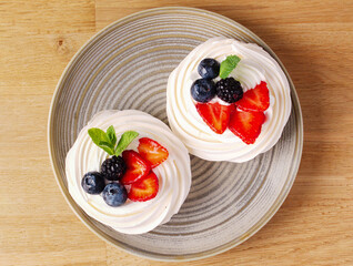 Delicious dessert of Pavlov's cake with fresh strawberries, blueberries and mint leaf. White dessert. Delicate meringue cake with berries. Cake on the table on March 8, Mother's Day, Valentine's Day.