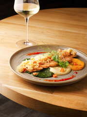 Chicken meat dish with multicolored vegetable puree and couscous. The concept of dietary nutrition. Delicious hot diet lunch dinner at the restaurant with a glass of wine or champagne. Copy space.