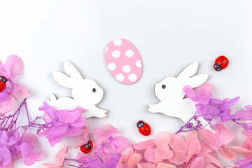 Colorful easter eggs with flowers and rabbits. Border design with pink spring flowers. Happy easter greetings concept, holiday decoration background with copy space, flat lay, top view photo